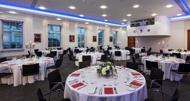 Round white tables spread throughout the room - set for dinner.