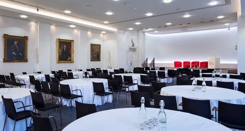 Round tables, adorned with white tablecloths, evenly stationed throughout the room.