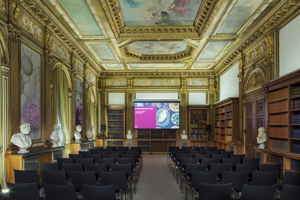 Rows of black chairs facing a projector screen.