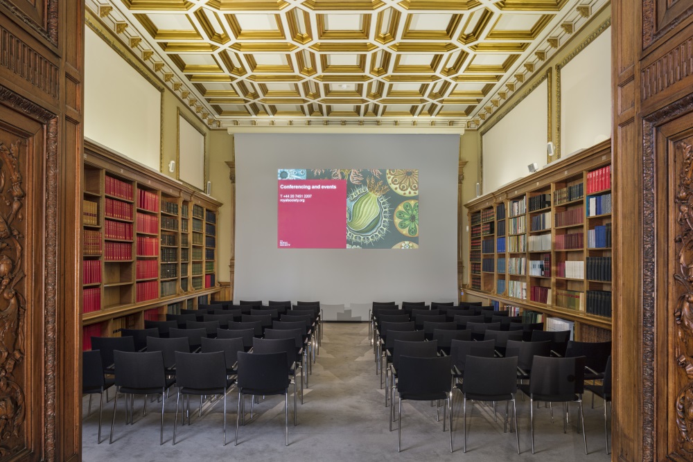 Rows of black chairs facing a projector screen.