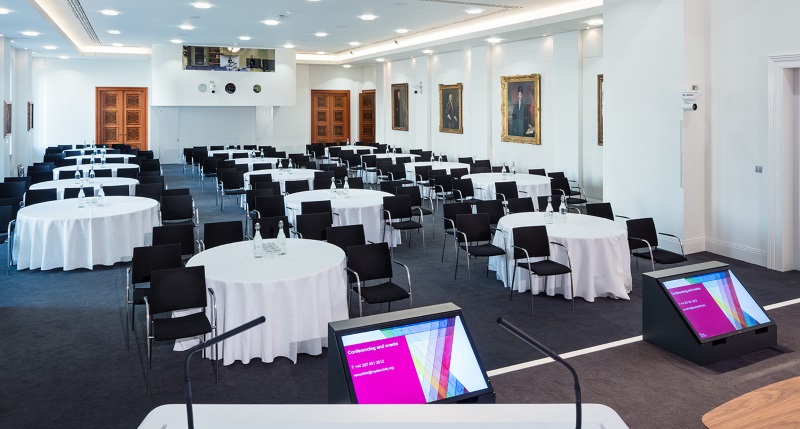 Round tables, adorned with white tablecloths, evenly stationed throughout the room.